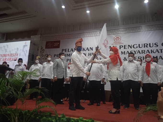 Ketua Badan Pengurus Pusat Perhumas Indonesia, Boy Kelana Subroto (masker hitam) menyerahkan bendera Perhumas kepada Ketua BPC Perhumas Pekanbaru, Rozita (jilbab merah) saat pelantikan di Ballroom Hotel Furaya, Pekanbaru, Ahad (24/7/2022).